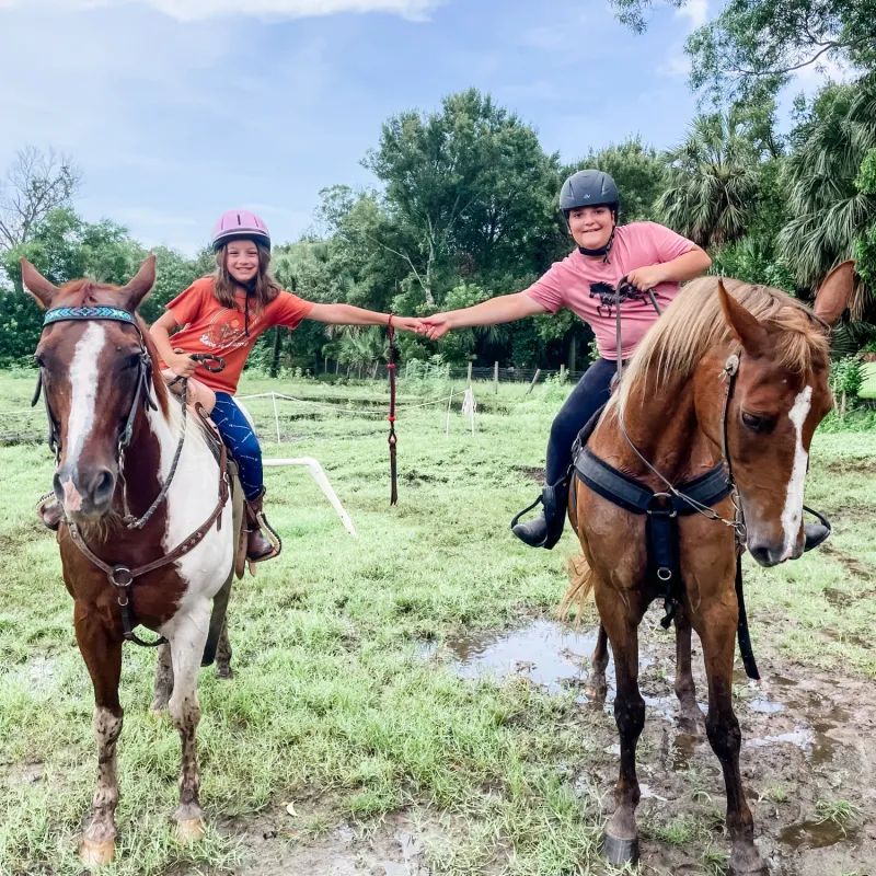 \Two girls horseback riding on a wooded trail during Equestrian Day at Jupiter Outdoor Center’s summer camp