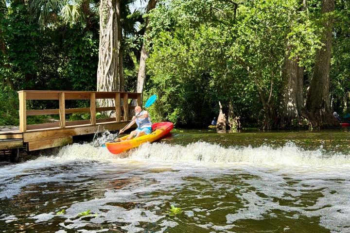 Kayaker paddling through small rapids called Lainhart Dam on the Wild and Scenic Loxahatchee River at Riverbend Park in Jupiter, Florida.