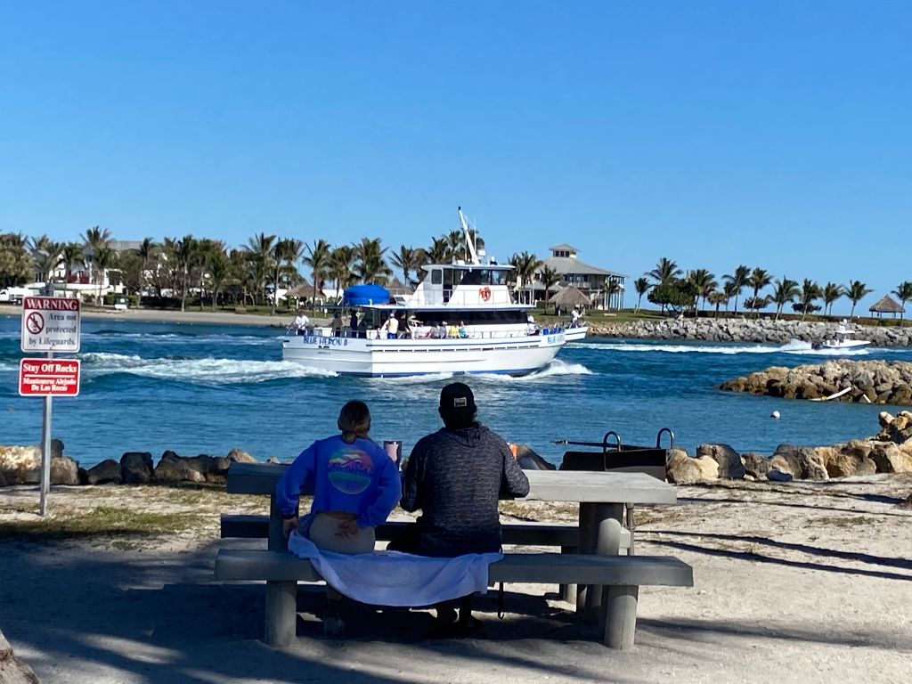 a group of people sitting on a bench next to a body of water